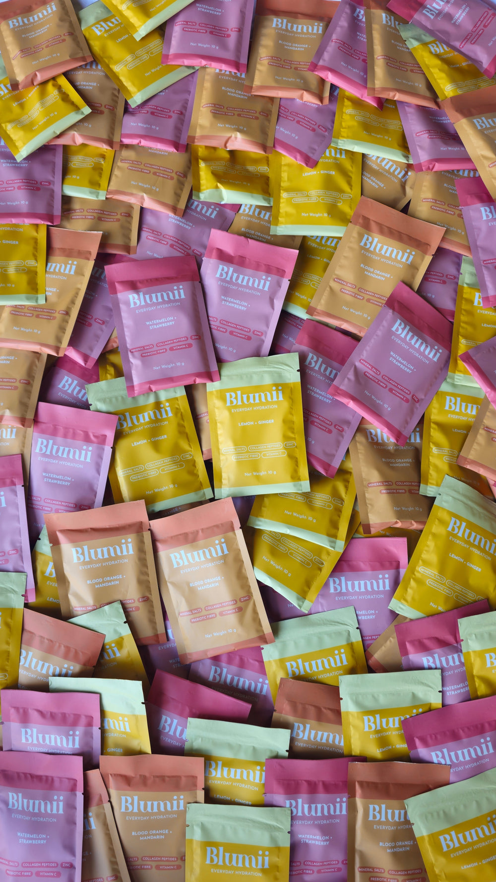 Blumii hydration blend electrolyte powder sachets in assorted pastel colours including pink, yellow, and orange.